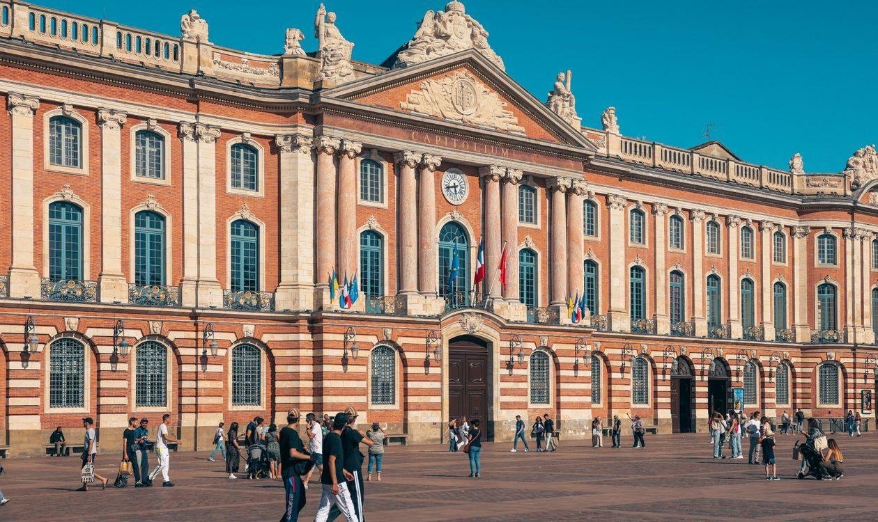 Place du Capitole à Toulouse avec la façade en briques roses et les passants