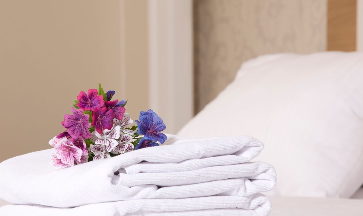 Serviettes blanches pliées et linge de maison préparés dans une chambre de location Airbnb