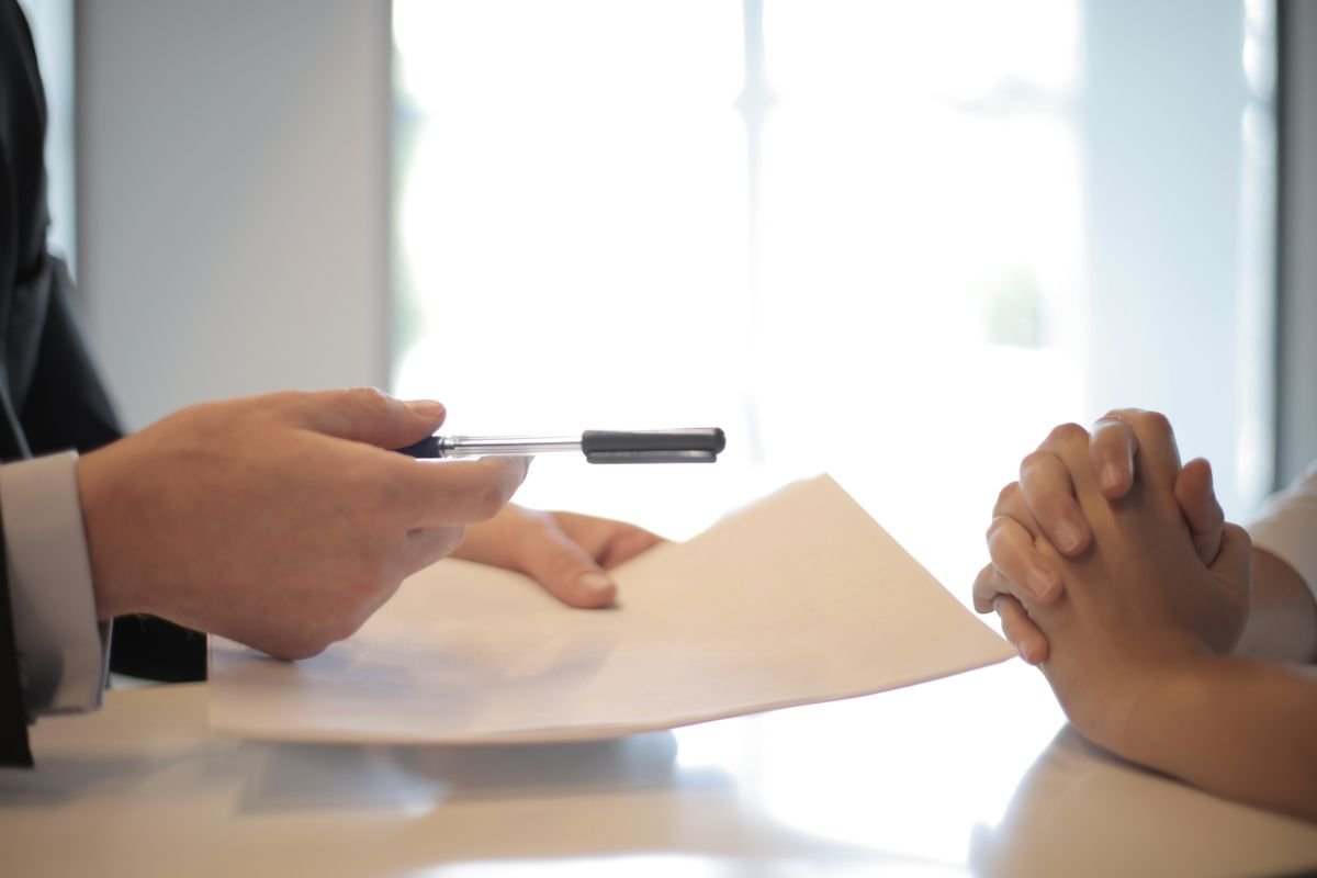 Signature d'un bail de location remis avec un stylo à un locataire dans un bureau lumineux