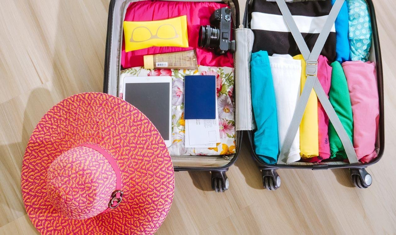 Valise ouverte avec appareil photo, chapeau et lunettes de soleil