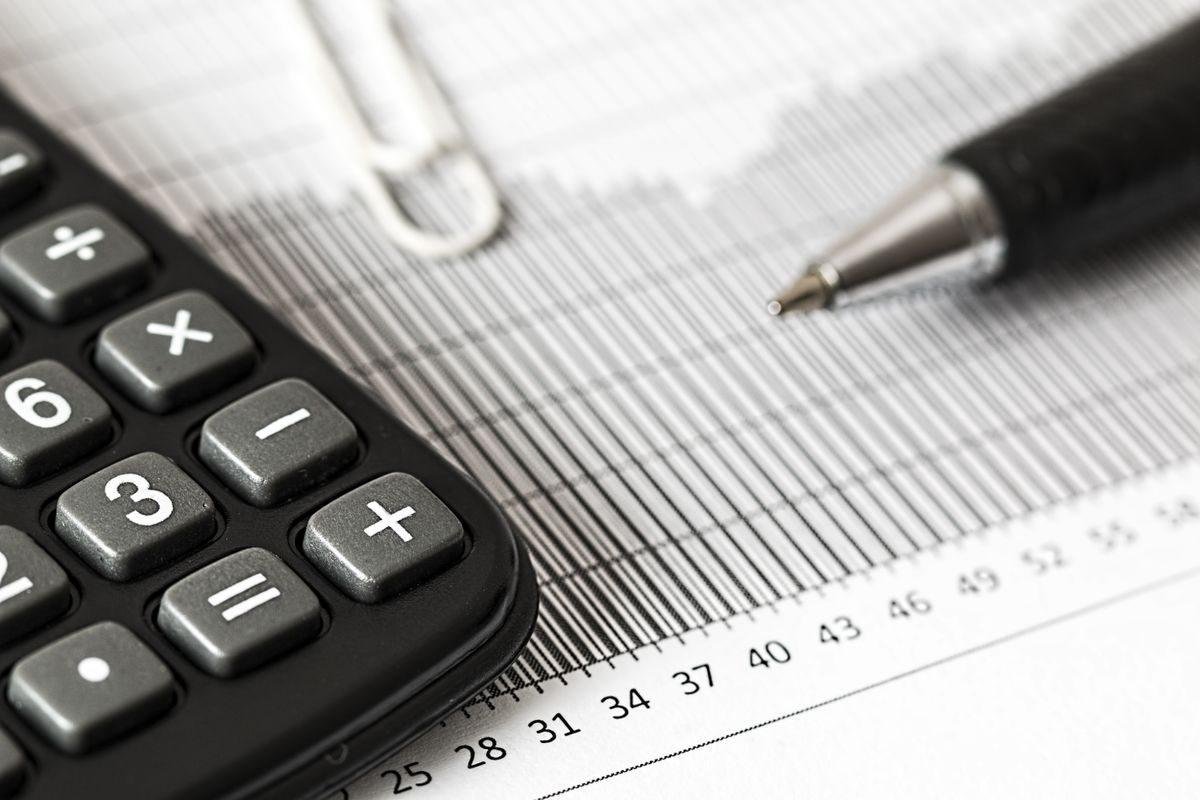 Calculatrice et stylo posés sur un relevé chiffré pour calculer la taxe d'habitation d'une location